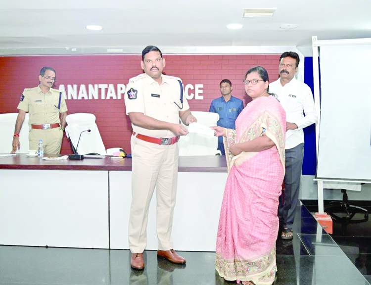 బాధితురాలికి చెక్కు అందజేస్తున్న ఎస్పీ శ్రీనివాసరావు
