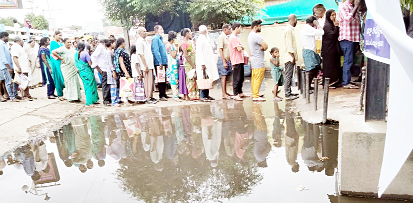 టమోటాల కోసం మురుగునీటి సమీపంలో క్యూలో వేచి ఉన్న ప్రజలు