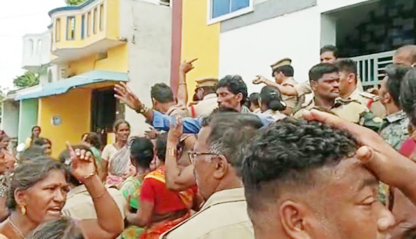 నిందితుల ఇళ్లపై దాడి చేస్తున్న ప్రజలను అడ్డుకుంటున్న పోలీసులు